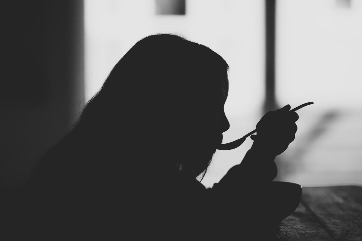 fekete-fehér képen egy lány eszik kanállal